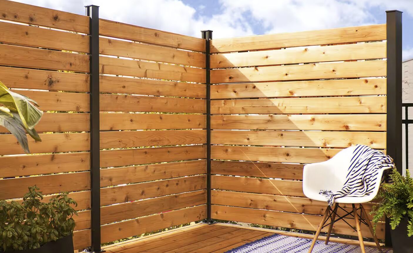 Modern horizontal cedar wood slat privacy fence with black steel posts on a residential deck in Laredo, TX